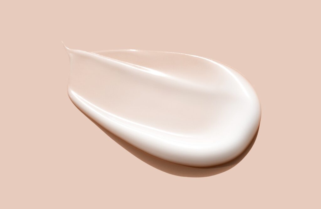 creamy smear of white cosmetic texture close up on beige background skin care concept